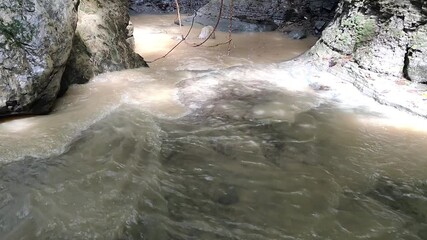 Wall Mural - Fast-flowing brown dirty and turbulent water after rain in Cave in the tropical jungle.