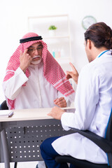 Wall Mural - Old male arab visiting young male doctor