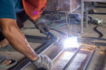 Wall Mural - The welder is welding the parts of the iron door. The person working on a welder using an electric welding machine.