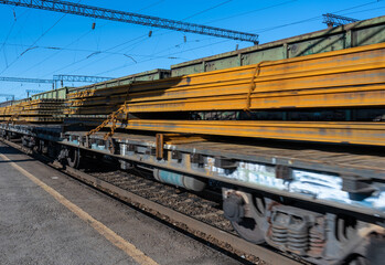 A train carrying rails arrives at the station