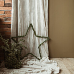 Wall Mural - Star symbol decoration made of fir branches on washed linen curtains, fir branches in basket. Minimalist home interior design concept decorated for Christmas celebration.