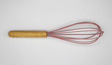 Top Down View On One Isolated Whisk With Wood Handle And Pink Wire Loops On Blank White Background