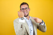 © Irene - Young handsome businessman wearing suit over isolated yellow background smiling and pointing his watch because it's late