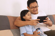 © airdone - Happy Asian father and baby girl daughter looking at tablet mobile phone, family enjoys quality time