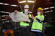 © torsakh - Manager or supervisor wear face mask talking or discussing with engineering team or worker about electrical drawing of machine control and operate in manufacturing factory, Covid or virus protection