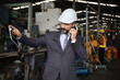 © torsakh - A smart professional business manager wear suit is working or inspect and radio to ordering in factory or production line, smart leader or entrepreneurship concept