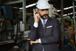 © torsakh - A smart professional business manager wear suit is working or inspect and radio to ordering in factory or production line, smart leader or entrepreneurship concept