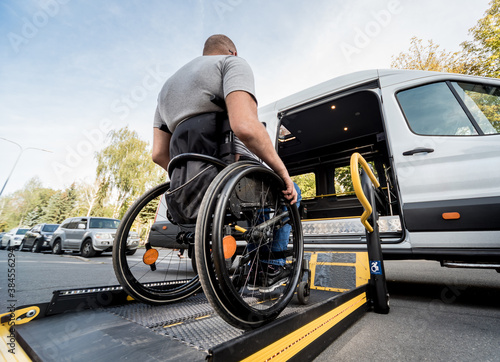 Fototapeta A man in a wheelchair moves to the lift of a specialized vehicle