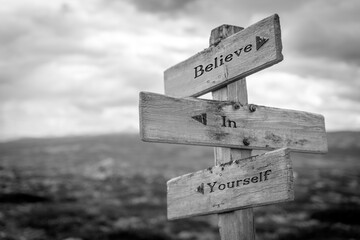 Wall Mural - believe in yourself text quote on wooden signpost outdoors in black and white.
