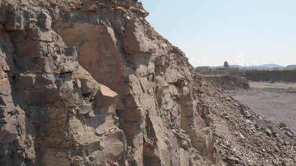 Close view of rocky soil structure in a mining quarry. Quarrying of stones. Blue shadows of mountains.