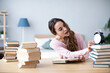 © BestForYou - Female student sits at a table with books preparing for exams.