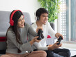 © Dollydoll - Asian man and woman using controler play  games at home. Quarantine time at home. Family bonding time.