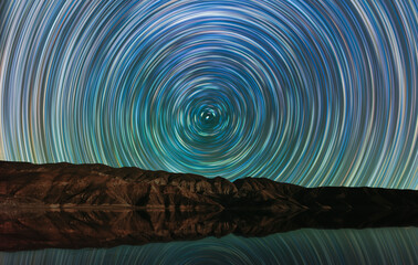 Wall Mural - long exposure night landscape. beautiful mountains and lake. colorful star trails on the sky. night 