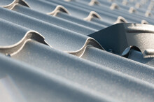 Gray Metal Roof Tiles And Snow Guards. House Roofing System Close-up.