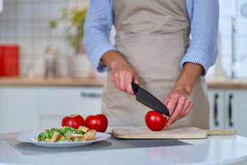 Wall Mural - Cooking woman cutting ripe fresh eco friendly juicy tomatoes on a wooden board using a knife