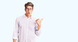 © Krakenimages.com - Young handsome man wearing business clothes and glasses surprised pointing with hand finger to the side, open mouth amazed expression.