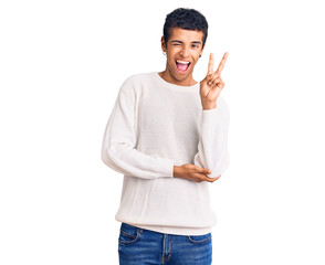 Young african amercian man wearing casual clothes smiling with happy face winking at the camera doing victory sign with fingers. number two.