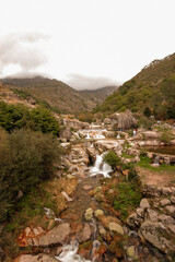 Wall Mural - stream runs between rocks with a mountain in background (Louriga - Portugal)