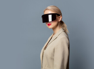 Wall Mural - Style blonde in futuristic VR glasses on gray background