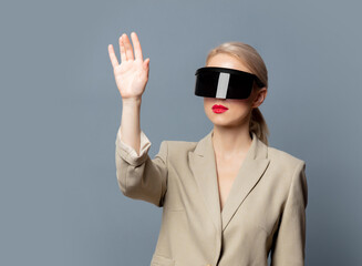 Wall Mural - Style blonde in futuristic VR glasses on gray background