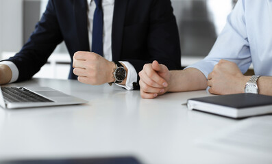 Unknown business people using laptop computer at the desk in modern office. Businessman or male entrepreneur is working with his colleague. Teamwork and partnership concept