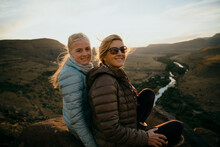 Caucasian Mother And Daughter Bonding While Watching Beautiful Sunset On Top Of Luscious Mountain