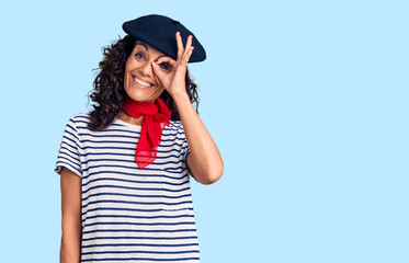 Wall Mural - Middle age beautiful woman wearing french beret and scarf smiling happy doing ok sign with hand on eye looking through fingers