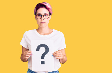 Poster - Young beautiful woman with pink hair holding question mark thinking attitude and sober expression looking self confident