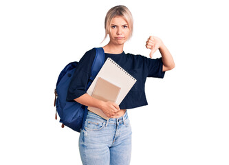 Canvas Print - Young beautiful blonde woman wearing student backpack holding notebook with angry face, negative sign showing dislike with thumbs down, rejection concept