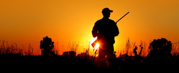a silhouette of a male hunter carrying a shotgun. he could be hunting pheasant, chukar, partridge, g