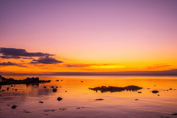 Wall Mural - Amazing view of glowing golden sunset over ocean and coastline rocks silhouettes