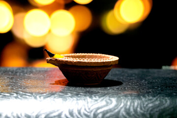 Wall Mural - Clay diya candle illuminated in Dipavali, Hindu festival of lights. Traditional oil lamp on dark background