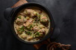Fricassee - French Cuisine. Chicken stewed in a creamy sauce with mushrooms in a black dutch oven on a black table 
