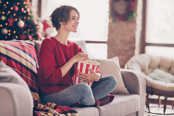 Wall Mural - Photo of cute young lady hold popcorn paper box eat sneck sitting couch look wear red sweater jeans socks indoors