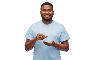 Wall Mural - grooming and people concept - smiling young african american man applying lotion or beard oil over white background