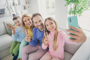 Poster - Photo of family people mom dad sit cozy sofa kid girl take selfie smartphone boy make v-sign in house indoors