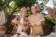 © zinkevych - Happy middle-aged couple shucking corn in the garden, smiling