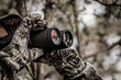hunter in a camouflage suit looks through binoculars on the hunt, close-up, soft focus