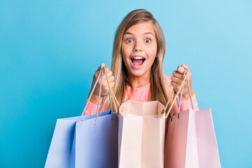 Sticker - Photo portrait of girl holding shopping bags with open mouth isolated on pastel blue colored background