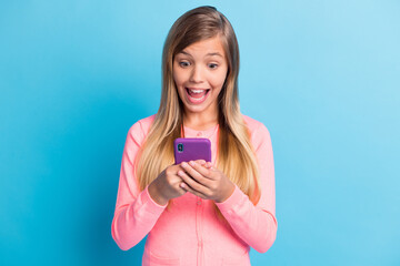 Photo portrait of shocked girl with open mouth holding phone in two hands isolated on pastel blue colored background