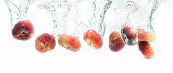 Wall Mural - Bunch of doughnut peaches isolated on white background, splashing into water.