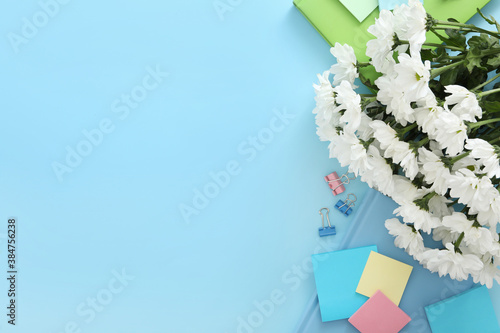 Beautiful flowers and stationery on light blue background, flat lay with space for text. Teacher\'s Day