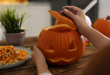 Sticker - Woman with pumpkin jack o'lantern at wooden table, closeup. Halloween celebration