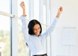 Portrait of happy excited black businesswoman with arms raised celebrating success