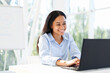 © GVS - Smiling african american businesswoman working on laptop sitting at her desk in modern office