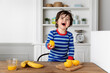 © Lisa Tichané - Laughing young boy at kitchen table holding a lemon