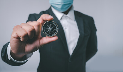 Poster - Businessman holding a navigation compass in hand with copy space background. business planning and Business navigate recovery for businessmen to resume business growth in the economic crisis.