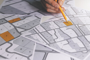 Wall Mural - hand with pencil on cadastral map - choose and buy a building plot for house construction