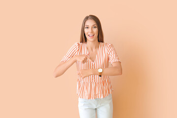 Wall Mural - Young woman with wristwatch on color background