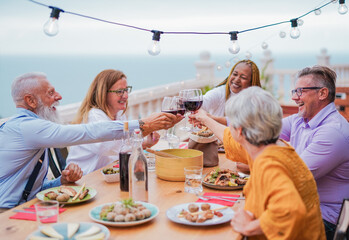 Multiracial senior people cheering with wine at dinner outdoor - Food and drink 